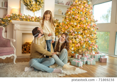 Young family feeeling happy sitting near the new year tree Young family feeeling happy sitting near the new year tree 71869238