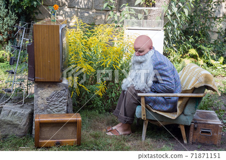 A sad grandfather sitting outside with TV A sad grandfather sitting outside with TV 71871151