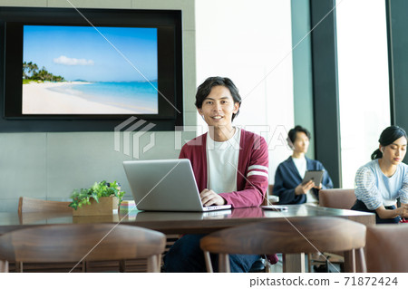 A young man working on a computer in a coworking space 71872424