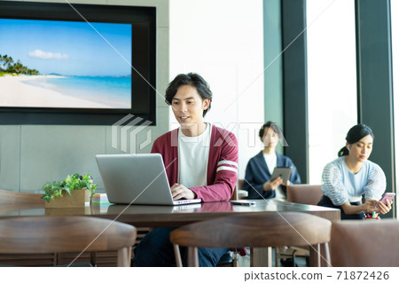 A young man working on a computer in a coworking space 71872426