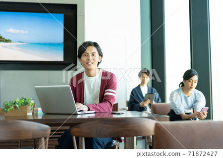 A young man working on a computer in a coworking space 71872427