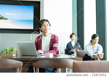 A young man working on a computer in a coworking space 71872431