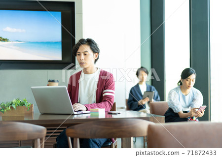 A young man working on a computer in a coworking space 71872433