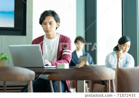 A young man working on a computer in a coworking space 71872435
