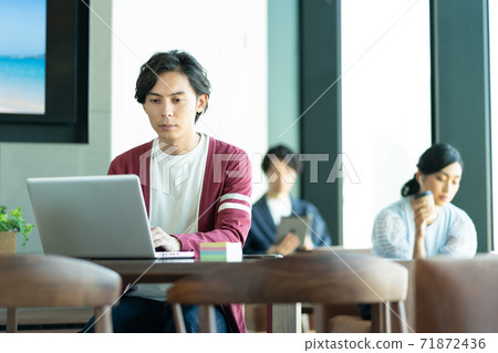 A young man working on a computer in a coworking space 71872436
