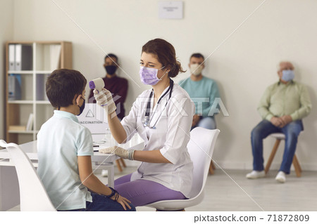Medical nurse measuring little boy's temperature using modern non-contact thermometer 71872809