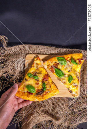 pizza Basil leaves on a black background, top view. vertical photo. Pizza with ham, meat, cheese, tomatoes and mushrooms. Two pieces. pizza Basil leaves on a black background, top view. vertical photo. Pizza with ham, meat, cheese, tomatoes and mushrooms. Two pieces. 71873098