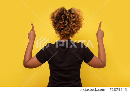 Rear view of a african woman with her hand up pointing. Pay attention to this information. 71873343