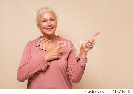 Amazed old woman pointing at copy space aside 71873608