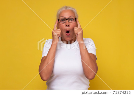 Shocked senior woman , keeping hands up looking with great surprisment and amazement into camera 71874255