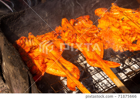 Grilled chicken with skewer cooked on charcoal barbecue stove background Grilled chicken with skewer cooked on charcoal barbecue stove background 71875666