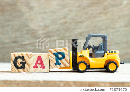 Toy forklift hold letter block P to complete word GAP (abbreviation of good agricultural practice) on wood background Toy forklift hold letter block P to complete word GAP (abbreviation of good agricultural practice) on wood background 71875670