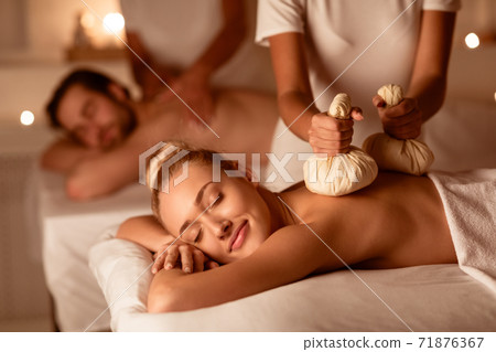 Couple Receiving Herbal Massage With Aromatic Bags Relaxing At Spa Couple Receiving Herbal Massage With Aromatic Bags Relaxing At Spa 71876367