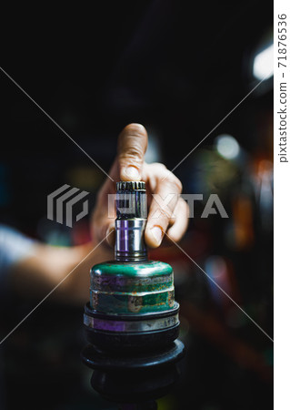 hand holding ATV constant-velocity CV joint, repair in old garage 71876536