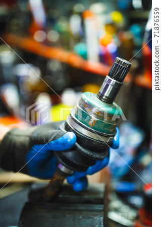 hand holding ATV constant-velocity CV joint, repair in old garage hand holding ATV constant-velocity CV joint, repair in old garage 71876559
