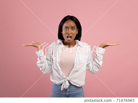 Annoyed African American woman gesturing I DON'T KNOW, shrugging her shoulders on pink studio background Annoyed African American woman gesturing I DON'T KNOW, shrugging her shoulders on pink studio background 71876965