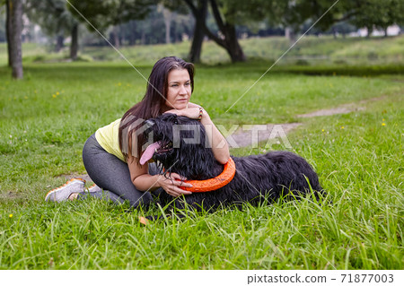 Girl hugs black long-haired dog while walking in park. Girl hugs black long-haired dog while walking in park. 71877003