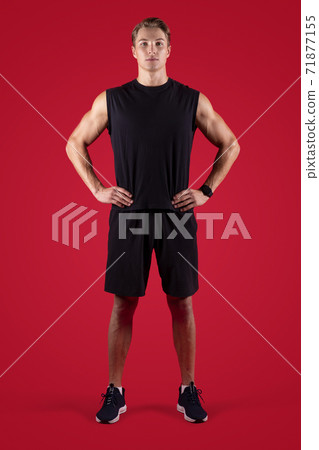 Full length portrait of determined male fitness model looking at camera on red studio background Full length portrait of determined male fitness model looking at camera on red studio background 71877155