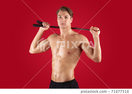 Motivated young guy with sexy body holding skipping rope on red studio background Motivated young guy with sexy body holding skipping rope on red studio background 71877318