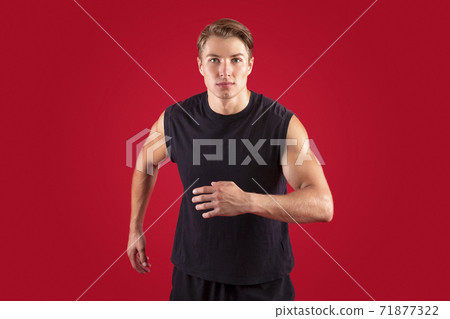 Sports and healthy lifestyle concept. Determined millennial athlete running on red studio background Sports and healthy lifestyle concept. Determined millennial athlete running on red studio background 71877322