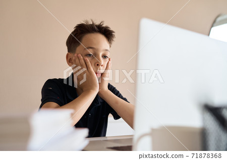 Smart looking boy doing his homework and look at computer notebook at home due to Covid-19 pandemic Smart looking boy doing his homework and look at computer notebook at home due to Covid-19 pandemic 71878368