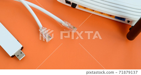 Internet router, portable USB wi-fi adapter and internet cable plugs lie on a bright orange background. Items required for internet connection 71879137