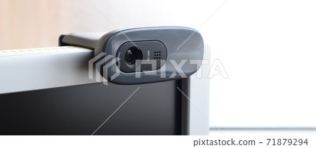A modern web camera is installed on the body of a flat screen monitor. Device for video communication and recording of high quality video 71879294