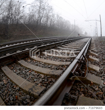 The railway track in a misty morning. A lot of rails and sleepers go into the misty horizon. Fisheye photo with increased distortion The railway track in a misty morning. A lot of rails and sleepers go into the misty horizon. Fisheye photo with increased distortion 71879683