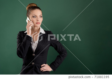 Smiling pretty businesswoman talks on the phone on green background 71881195