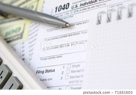 The pen, notebook, calculator, and dollar bills is lies on the tax form 1040 U.S. Individual Income Tax Return. The time to pay taxes 71881603