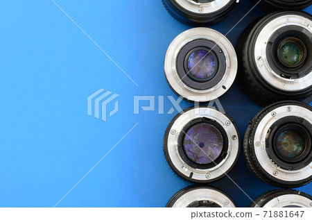 Several photographic lenses lie on a bright blue background. Space for text Several photographic lenses lie on a bright blue background. Space for text 71881647