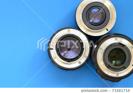 Several photographic lenses lie on a bright blue background. Space for text 71881710