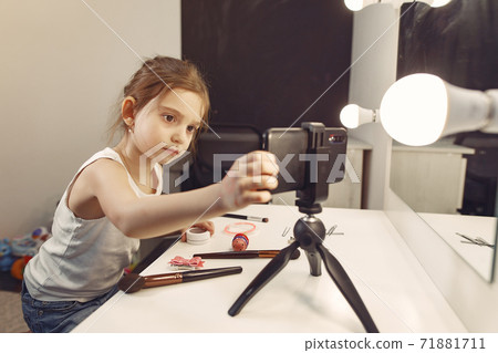 Cute little blogger with cosmetics recording video at home 71881711