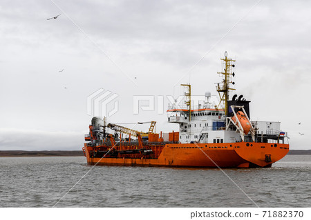Vessel engaged in dredging. Dredger working at sea. Ship excavating material from a water environment. 71882370