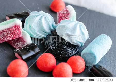 Sweets black licorice candies, colorful fruit marmalade in sugar and marshmallow scattered messy on a black table. 71882955
