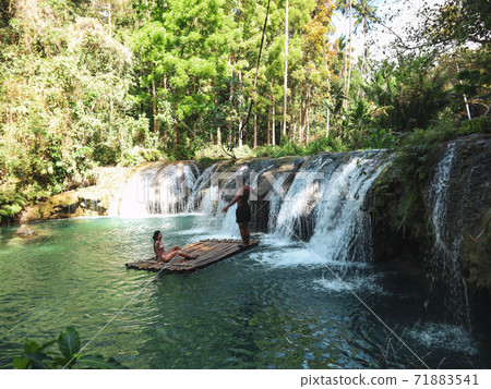 Lovely travel couple at the tropical wild nature adventure on the bamboo raft in Cambugahay Waterfalls in Siquijor Island, Philippines  71883541