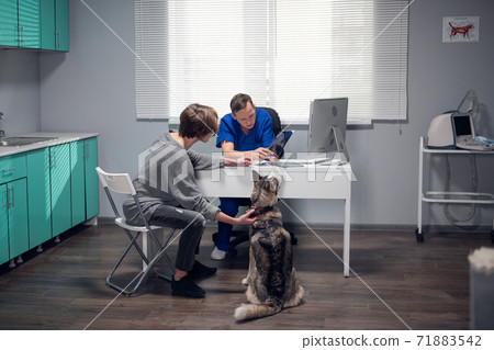 A doctor is talking to a young woman about her dogs diagnosis, they are discussing an x-ray 71883542