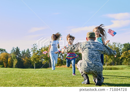 Soldier is meeting his family outdoors. 71884728