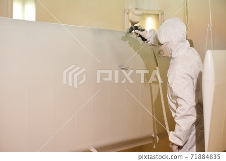 Worker spray painting metal. 71884835
