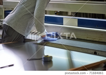 Worker is pressing a metal sheet. 71884861