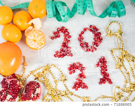 2021 number made from pomegranate seeds, fruits and tape measure on the table  71886005