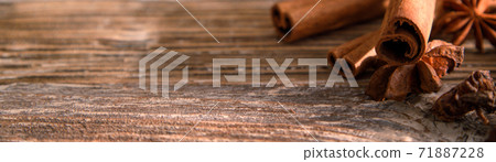 anise stars and cinnamon sticks with apples on a wooden table.  71887228