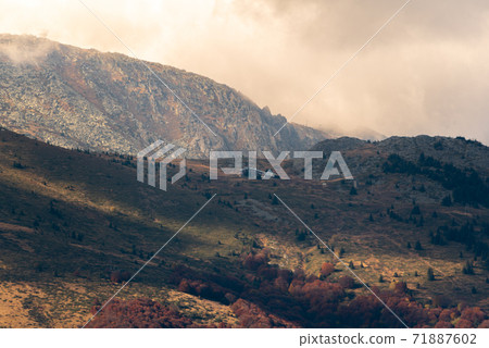 Autumn landscape in the mountains cloudy day sunrays wooden cottage on a ridge warm beautiful nature Autumn landscape in the mountains cloudy day sunrays wooden cottage on a ridge warm beautiful nature 71887602