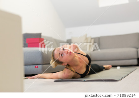 Beautiful blonde woman doing home workout indoors. Woman practice yoga at home. Fit girl using workout tutorials for healthy active lifestyle. Woman using quarantine for home workouts. Beautiful blonde woman doing home workout indoors. Woman practice yoga at home. Fit girl using workout tutorials for healthy active lifestyle. Woman using quarantine for home workouts. 71889214