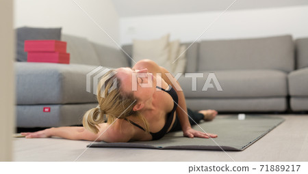 Beautiful blonde woman doing home workout indoors. Woman practice yoga at home. Fit girl using workout tutorials for healthy active lifestyle. Woman using quarantine for home workouts. 71889217