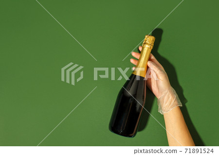 Medical latex Gloved hands hold a bottle of champagne on natural green background, hard shadows. Party concept, winter holiday in terms of pandmias, coronavirus, self-isolation, banner, copy space 71891524