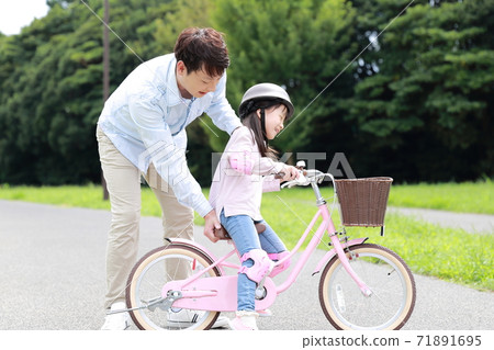 Parents and children practicing by taking training wheels on their bicycles 71891695