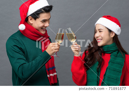 Asian couple in red and green clothes drinking champagne celebrating Christmas Asian couple in red and green clothes drinking champagne celebrating Christmas 71891877