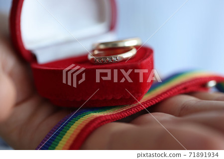 On hand lying box with wedding rings and ribbon with rainbow colors closeup On hand lying box with wedding rings and ribbon with rainbow colors closeup 71891934