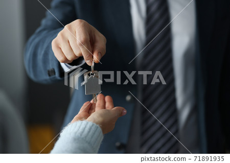 Man in business suit hands overing house keys to woman closeup 71891935